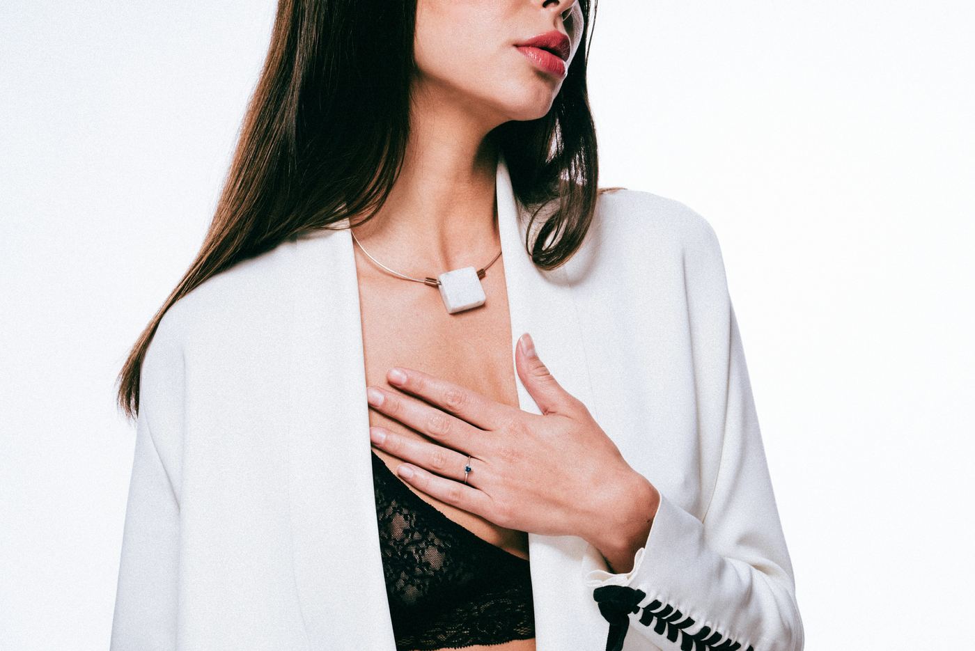Woman in a white cardigan with her hand on her chest