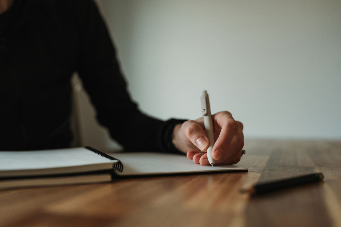 Hand writing in a notebook on a wooden table