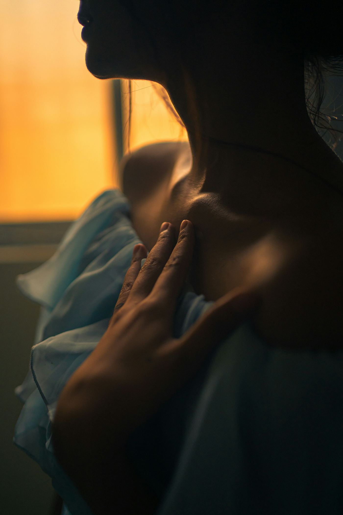 Person in a dim room with a hand on their chest