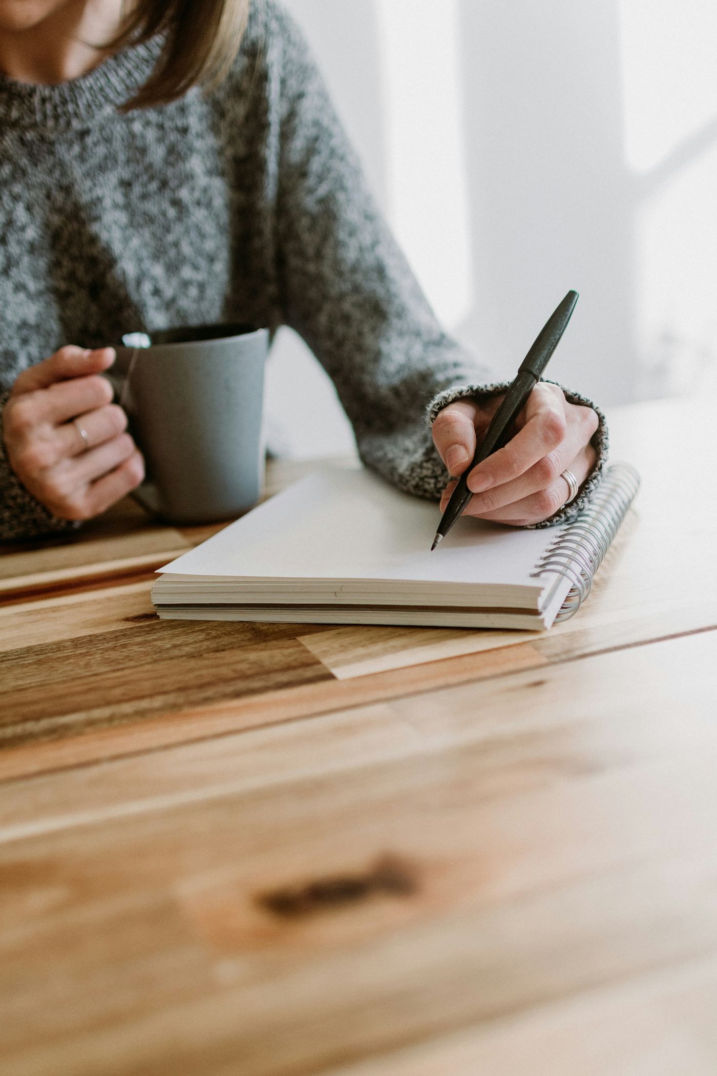 Woman writing in a notebook with a mug of tea